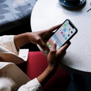 A person checks social media apps on a smartphone while sitting at a café table.